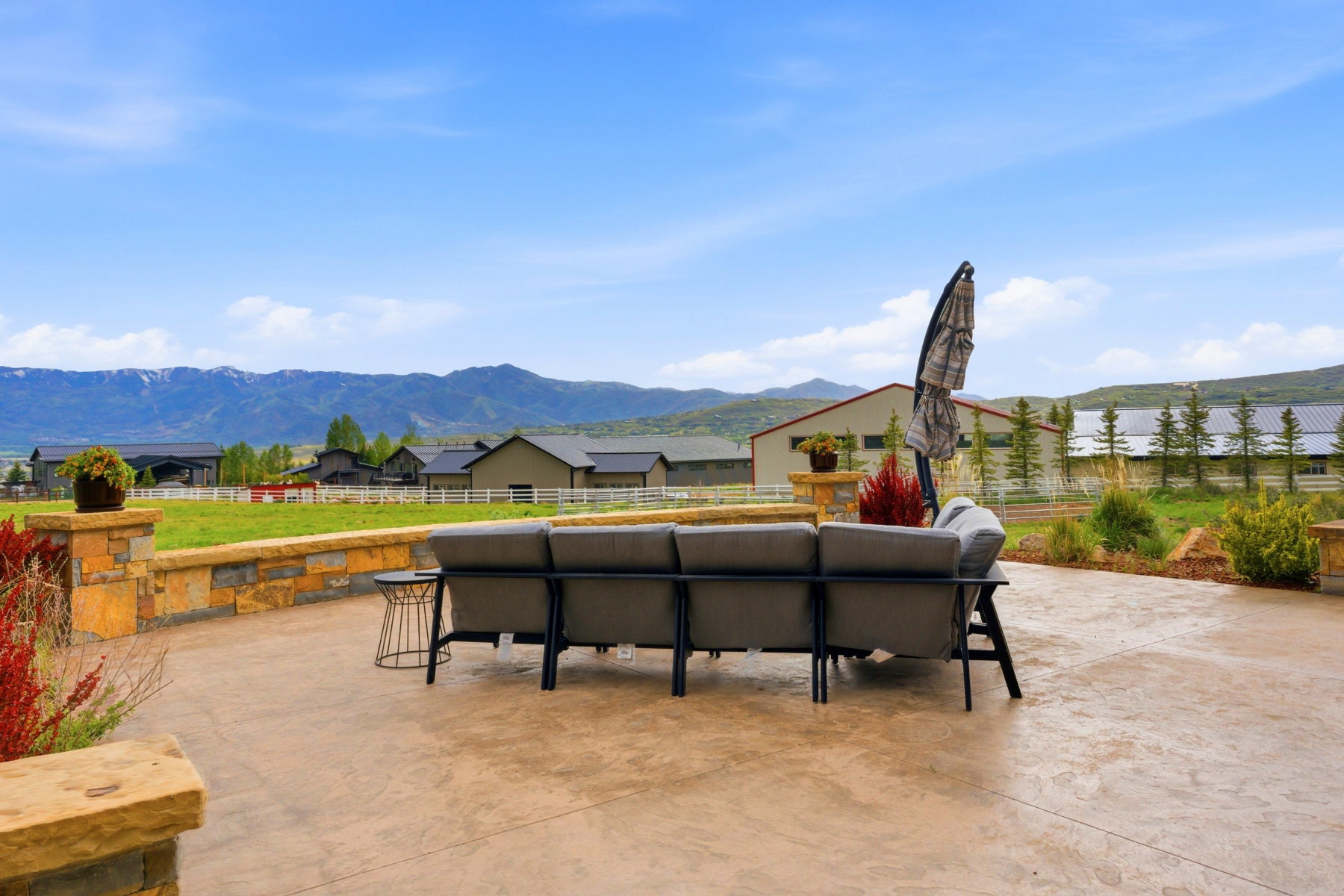 Expansive stamped concrete patio featuring a low stone retaining wall with matching pillars