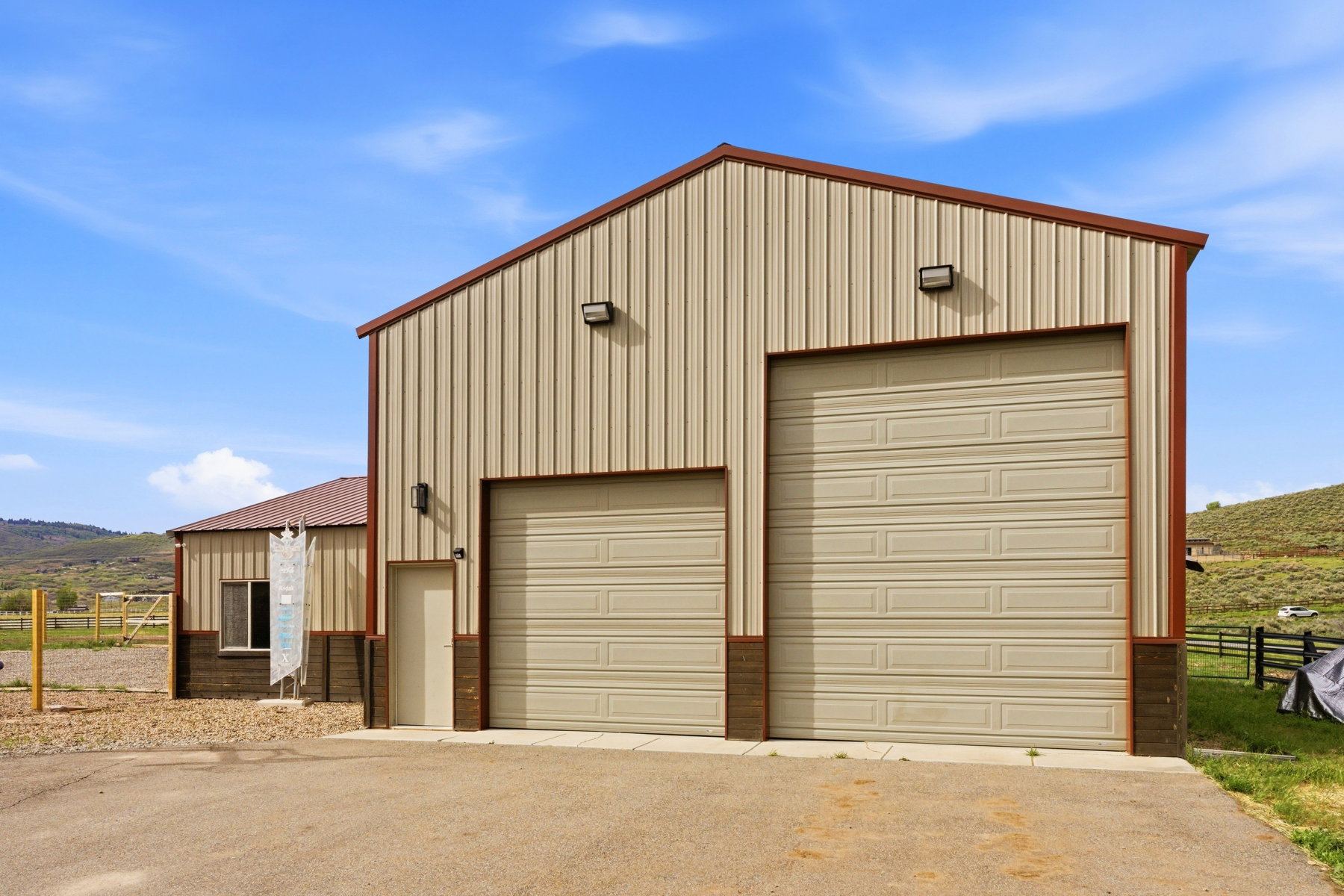 Large utility building featuring two roll-up garage doors, a pedestrian entry door, and exterior lighting fixtures