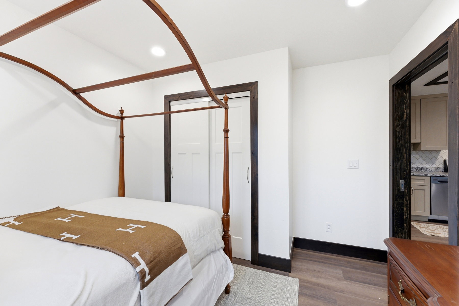 Recessed lighting illuminates this space featuring wood-finish flooring and crisp white walls