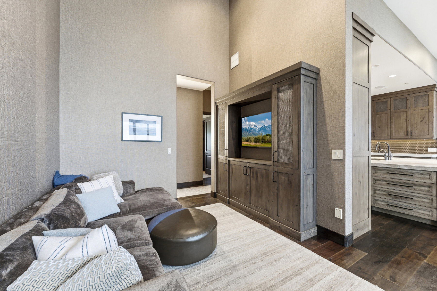 Living area featuring a custom built-in entertainment center, high ceilings, textured wall coverings, and dark wood-finish flooring