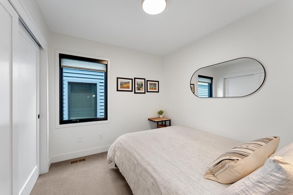 Bright interior space featuring a window with black trim, light-colored carpeting, white walls, and a ceiling light fixture