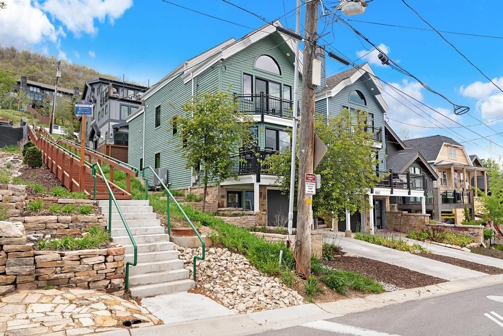 Modern multi-story residence featuring light green siding and prominent arched windows