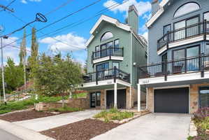 Three-story property featuring light green siding and black trim accents