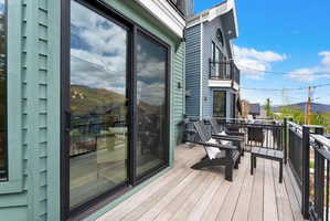 Private outdoor deck featuring composite decking, black metal railings, and sliding glass doors