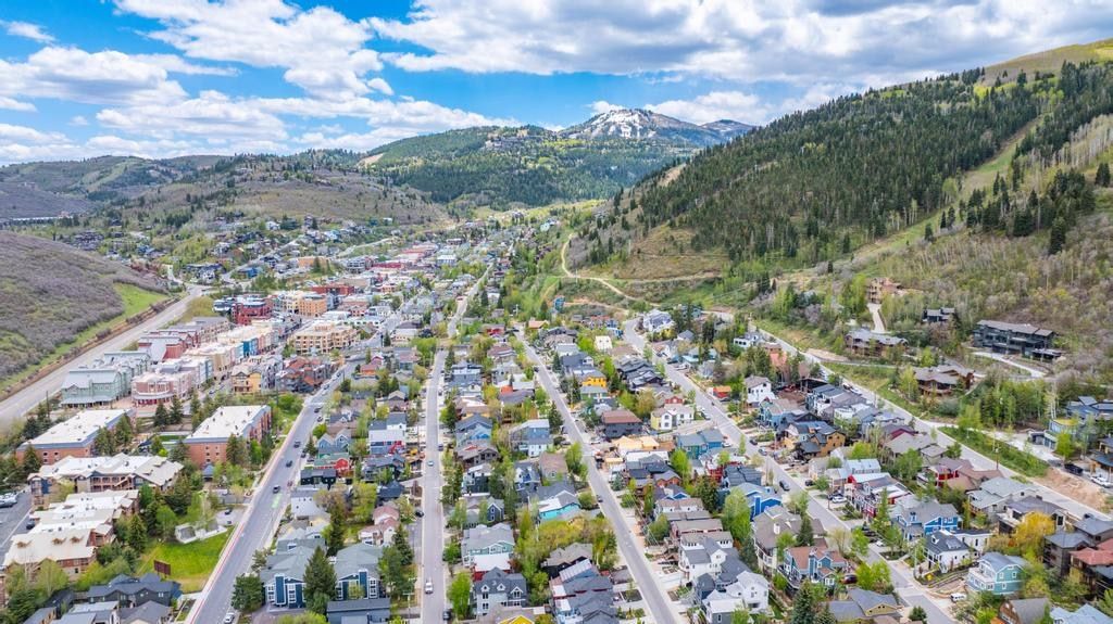 Aerial panorama showcasing a mountain community with diverse architectural styles, tree-lined streets, and distant peaks