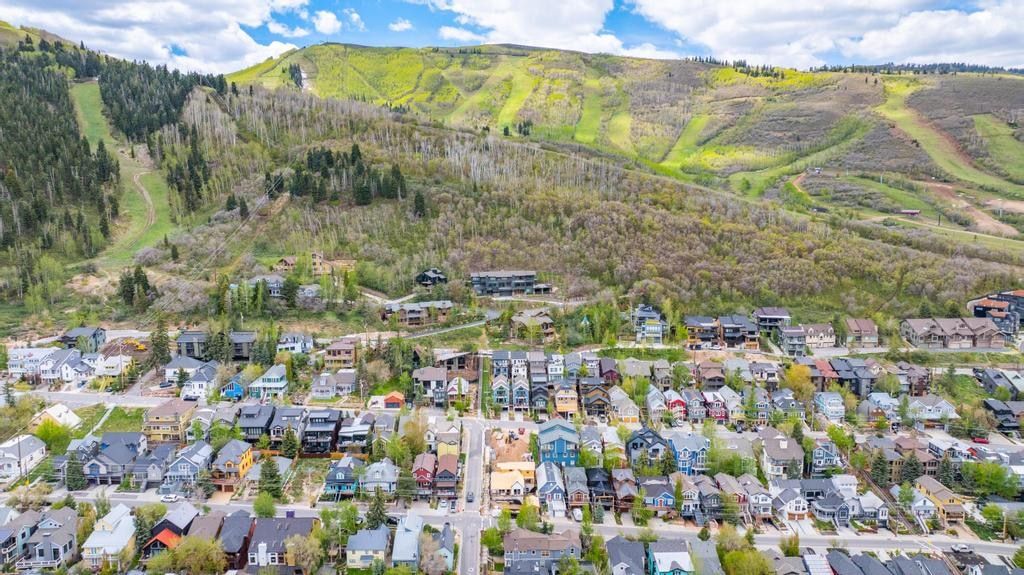 Aerial perspective showcasing a vibrant residential community nestled at the base of a verdant mountain