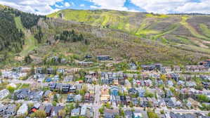 Aerial perspective showcasing a vibrant residential community nestled at the base of a verdant mountain