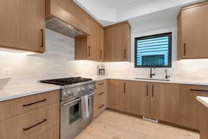 Modern kitchen featuring wood-finish cabinetry, white subway tile backsplash, and light-toned countertops