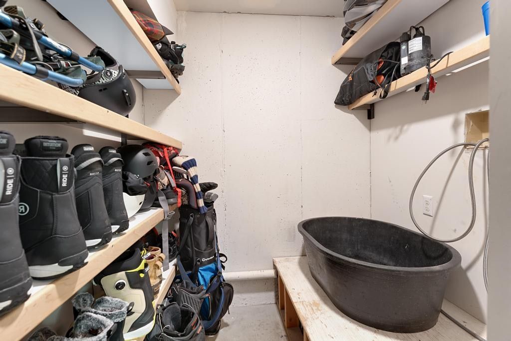 Dedicated utility area featuring a wall-mounted hose connection, a deep basin, and integrated wood shelving