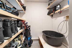 Dedicated utility area featuring a wall-mounted hose connection, a deep basin, and integrated wood shelving