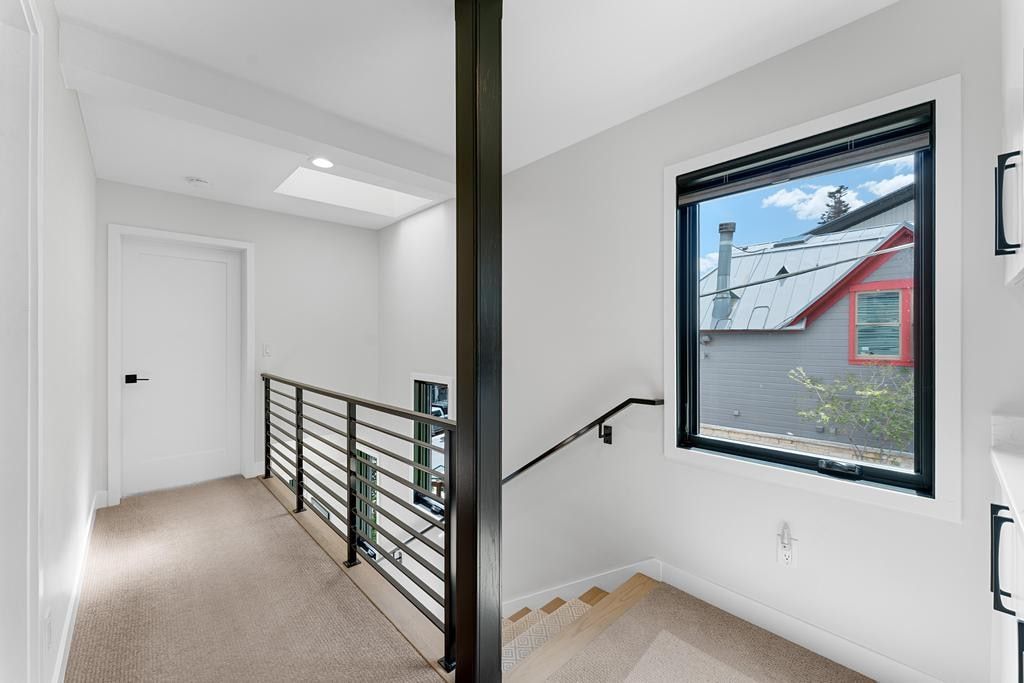 Upper-level landing featuring a skylight, light-colored carpeting, and a modern horizontal bar railing