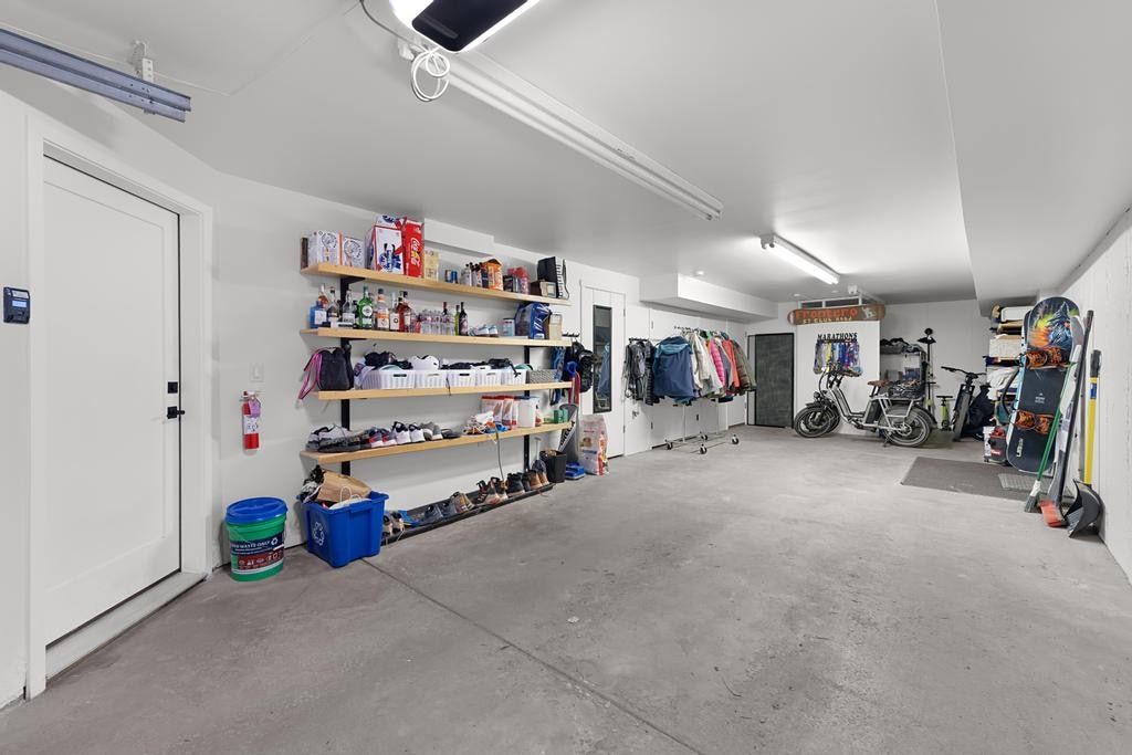 Spacious garage with concrete flooring, white walls, and overhead fluorescent lighting