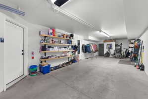 Spacious garage with concrete flooring, white walls, and overhead fluorescent lighting