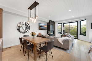 Open-concept living space featuring wood-finish flooring, a modern fireplace, and a shiplap ceiling