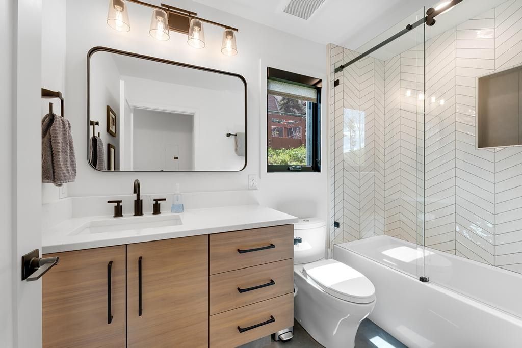 Modern bathroom featuring a wood-finish vanity with ample storage, a white countertop, and matte black fixtures