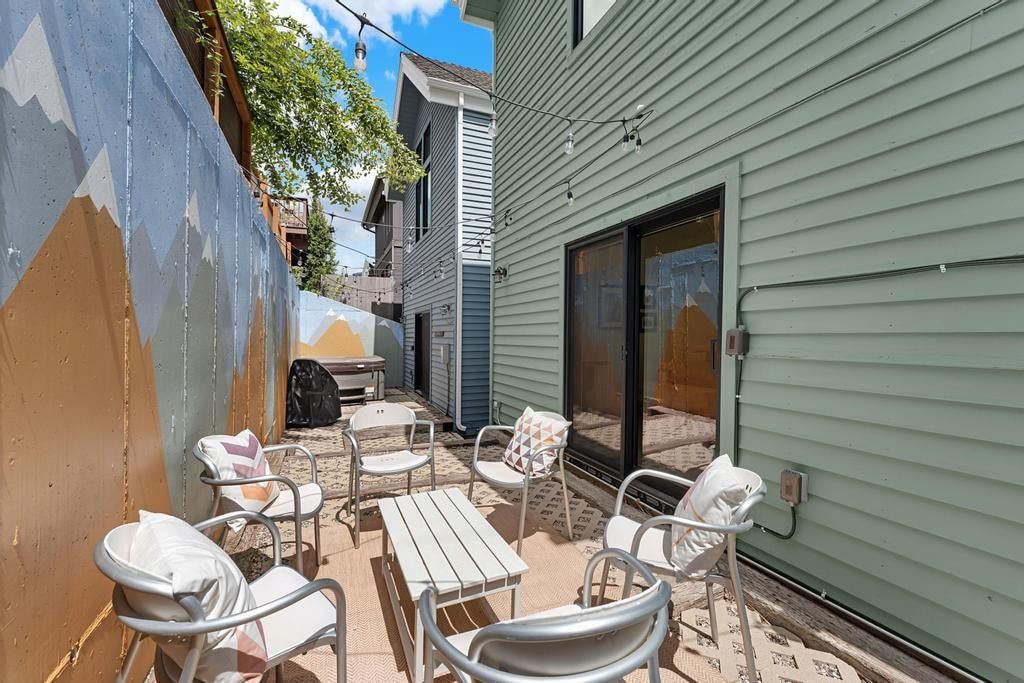 Paved patio area featuring string lighting, a painted privacy fence, and direct access to the interior via a sliding glass door
