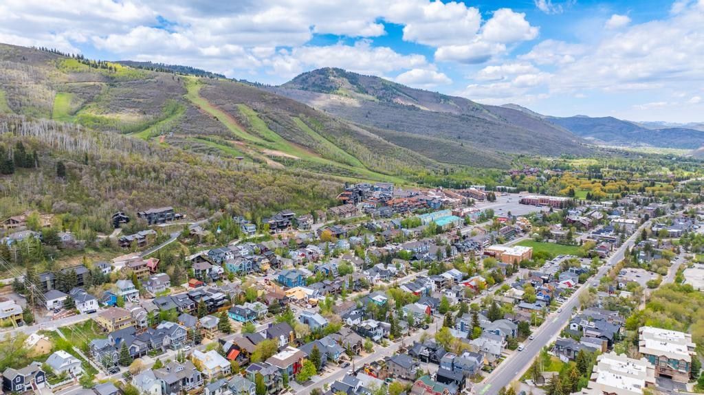 Aerial perspective showcasing a residential neighborhood nestled at the base of a verdant, mountainous landscape