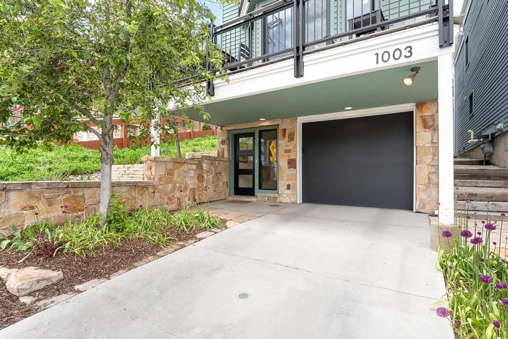 Entryway featuring a black garage door, stone veneer accents, and a concrete driveway