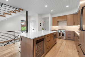 Open-concept kitchen with light wood-finish flooring, a white shiplap ceiling, and recessed lighting