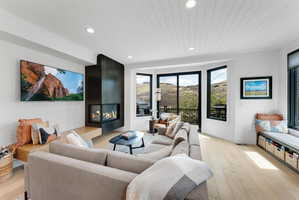 Spacious living area featuring light wood-finish flooring, a contemporary fireplace with a dark metal surround, and a built-in bench seat with integrated storage