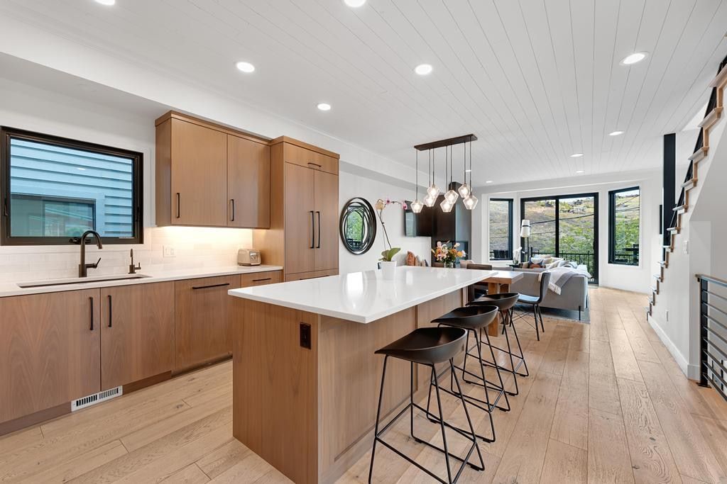 Modern kitchen featuring light wood-finish cabinetry and a white countertop island with seating