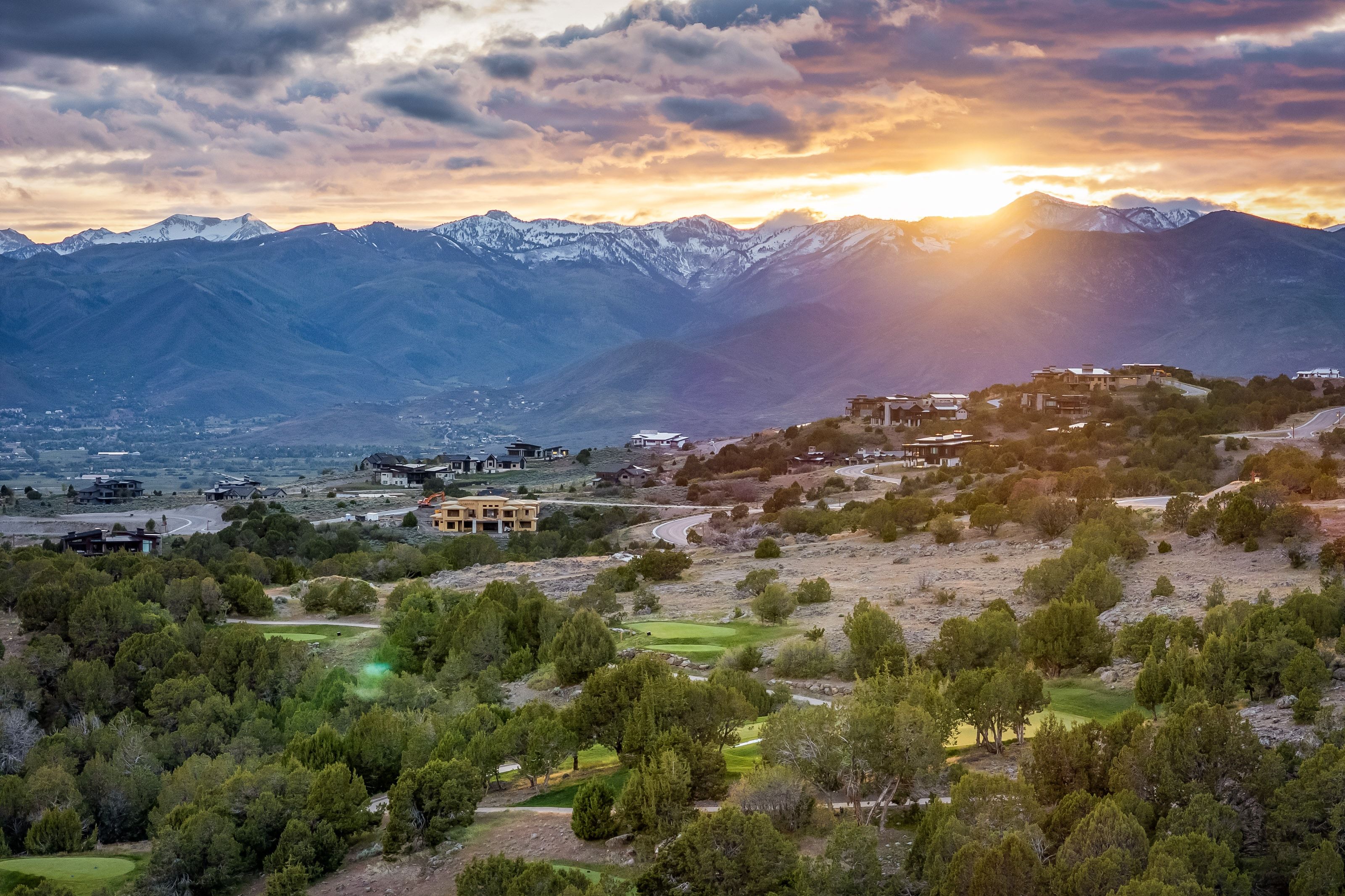 Expansive mountain landscape featuring snow-capped peaks and a golf course