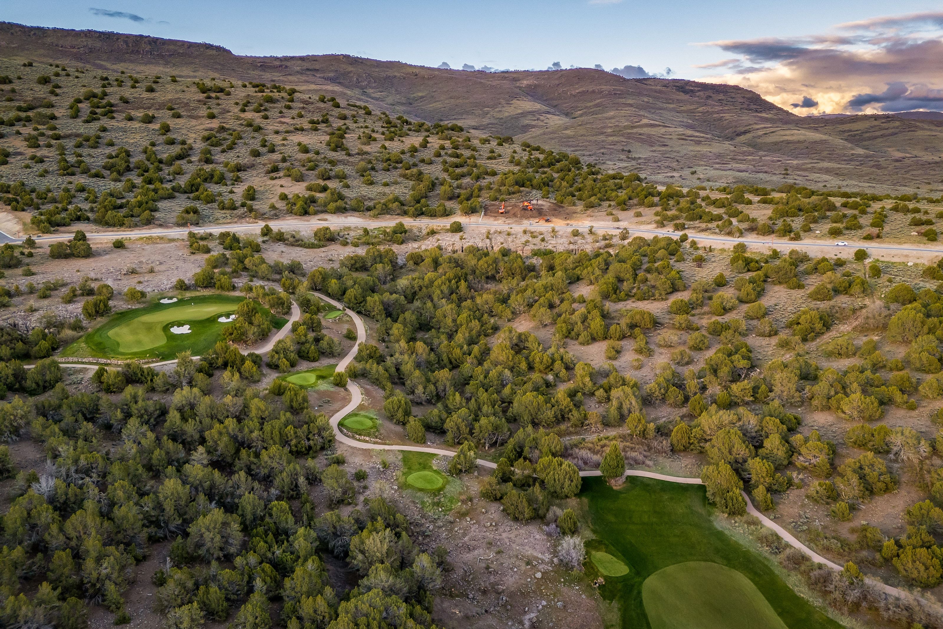 Expansive golf course terrain featuring multiple greens and sand bunkers