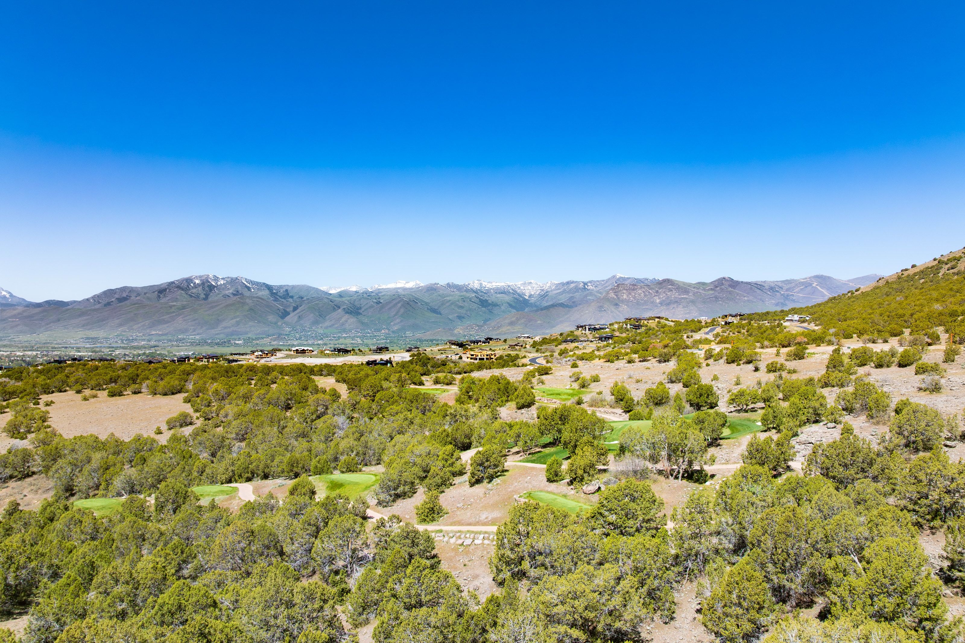 Expansive hillside property featuring established trees, mountainous terrain, and distant snow-capped peaks
