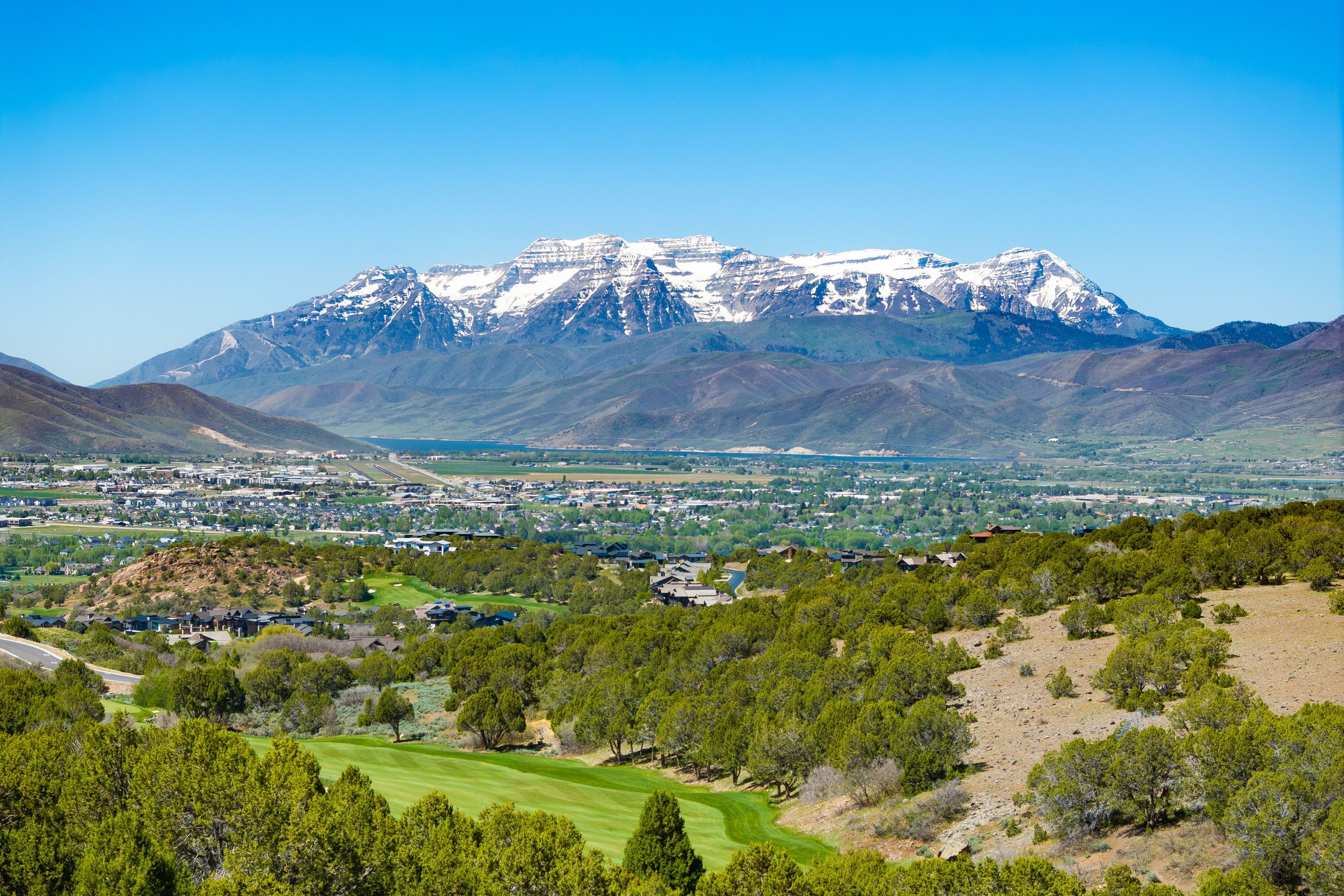 Snow-capped mountains provide a scenic backdrop to a distant residential area