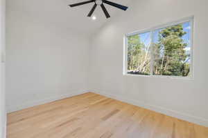 Room featuring light wood-finish flooring, a large window with white trim, and a modern ceiling fan