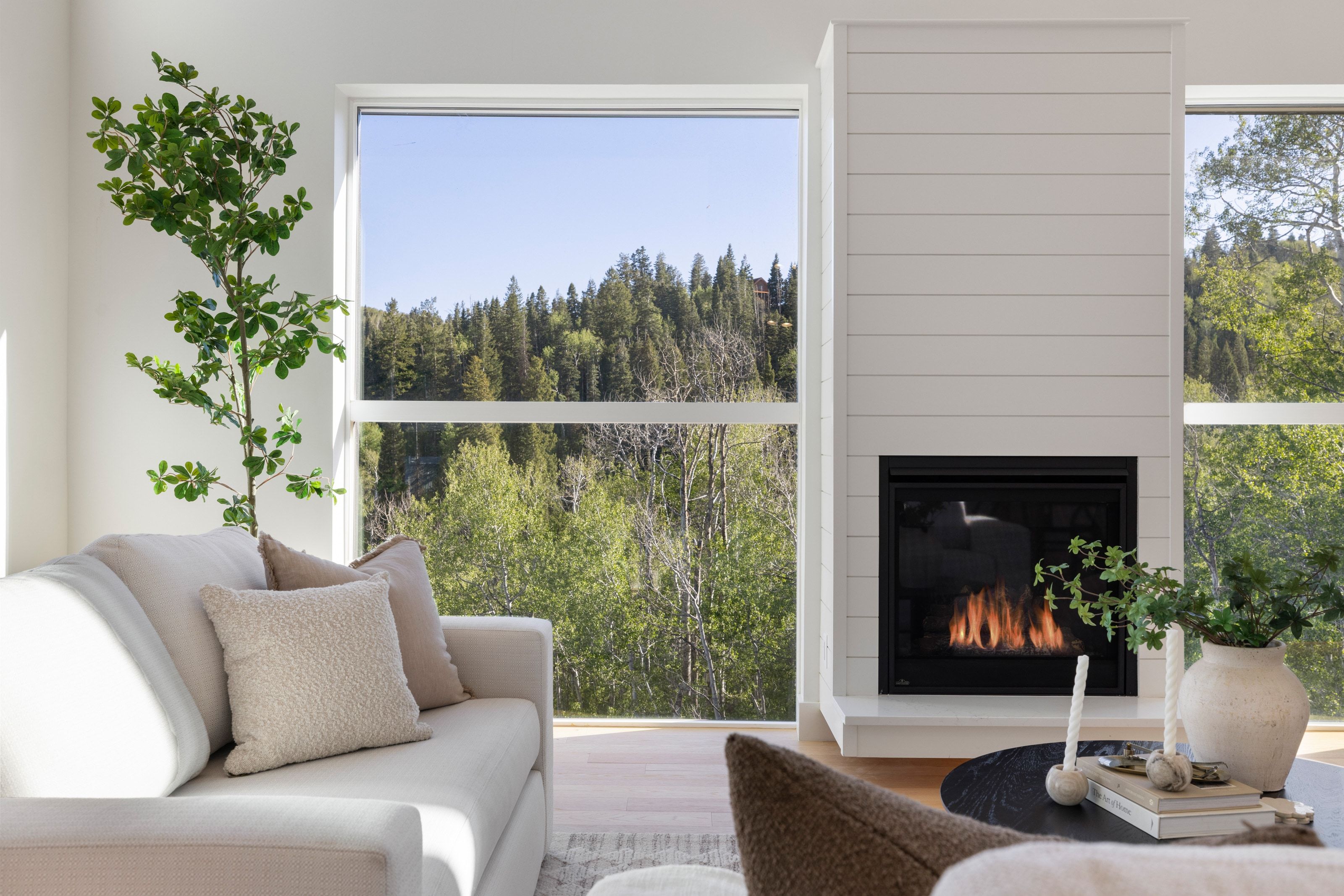 Fireplace with shiplap surround, large windows, and light wood-finish flooring