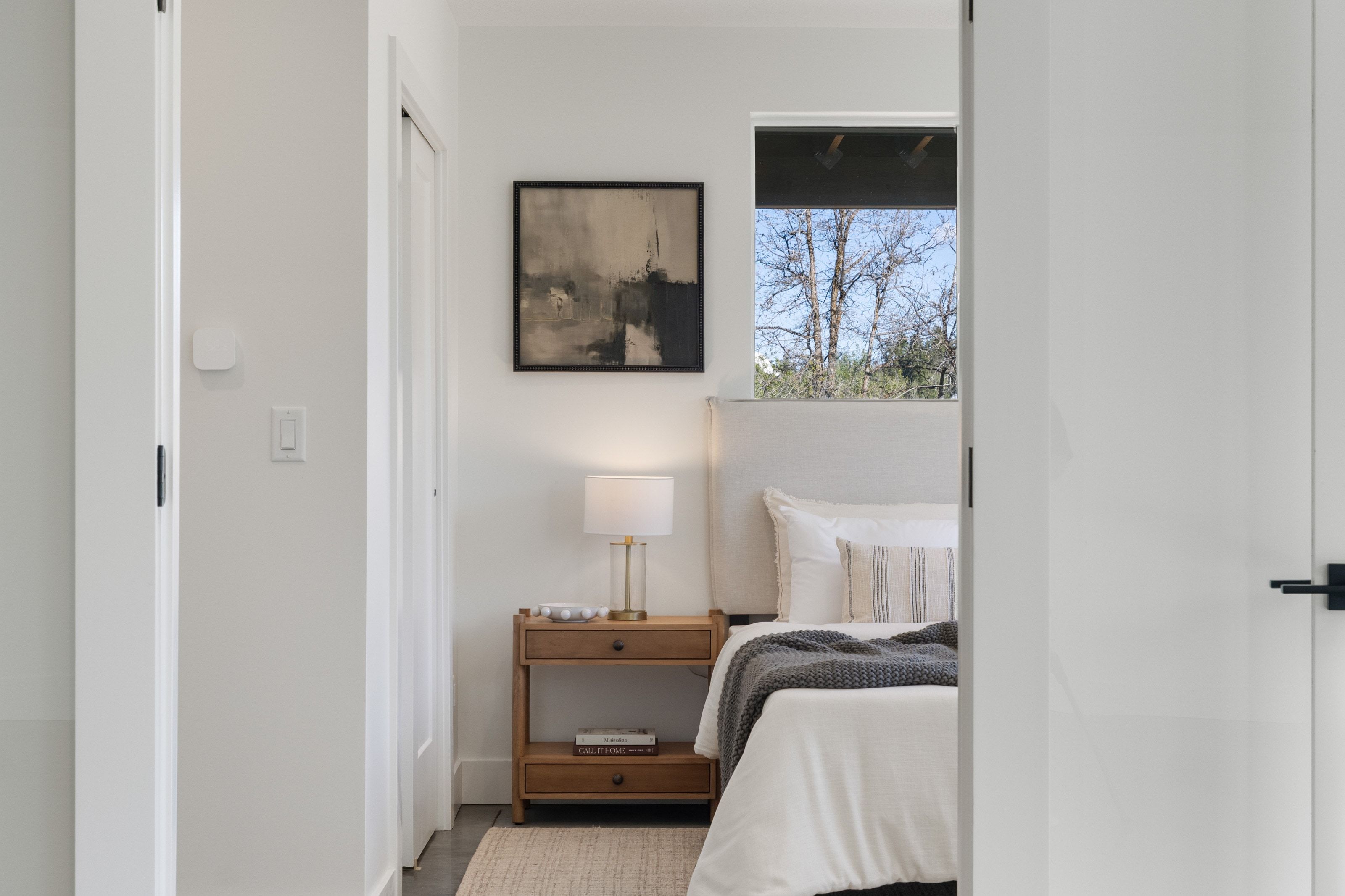 Bedroom featuring an upholstered headboard, wood-finish nightstand, and a window with natural light