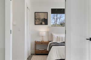 Bedroom featuring an upholstered headboard, wood-finish nightstand, and a window with natural light