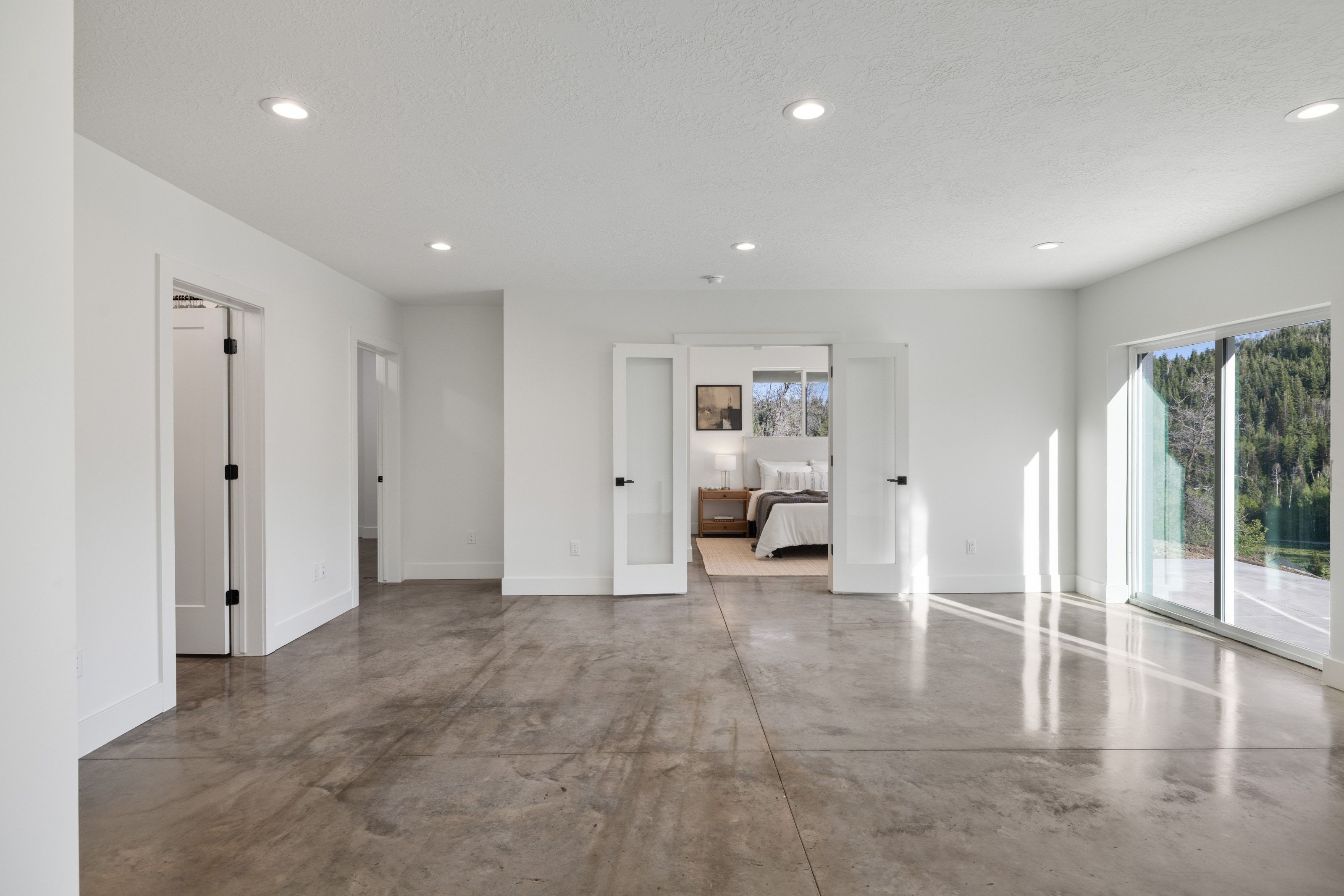 Open concept space featuring polished concrete flooring, recessed lighting, white walls, and a large sliding glass door