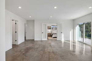 Open concept space featuring polished concrete flooring, recessed lighting, white walls, and a large sliding glass door