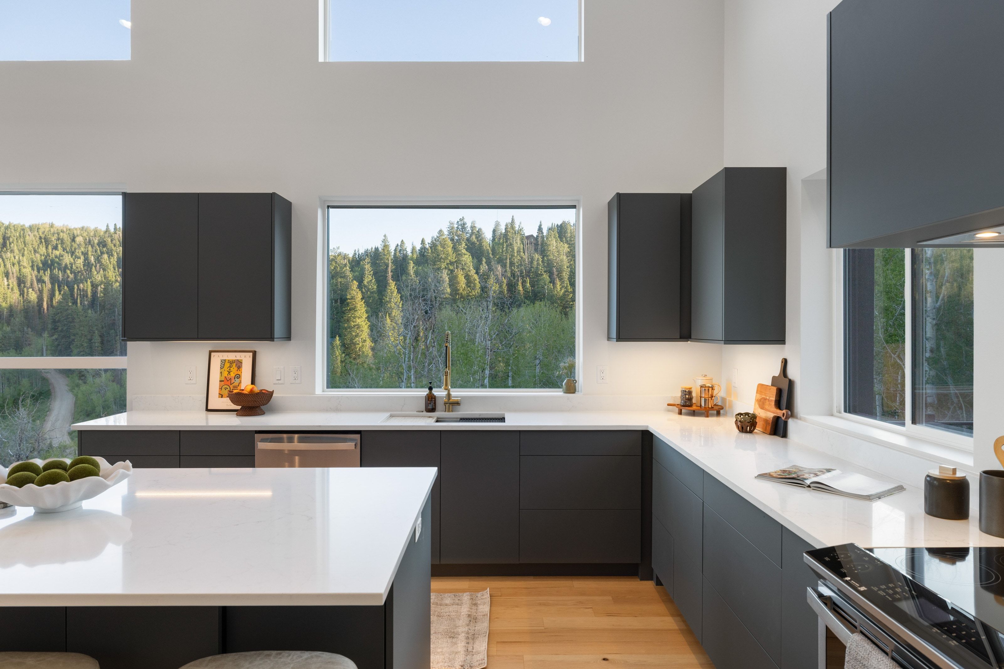Modern kitchen featuring dark cabinetry, light countertops, wood-finish flooring, and a large central island