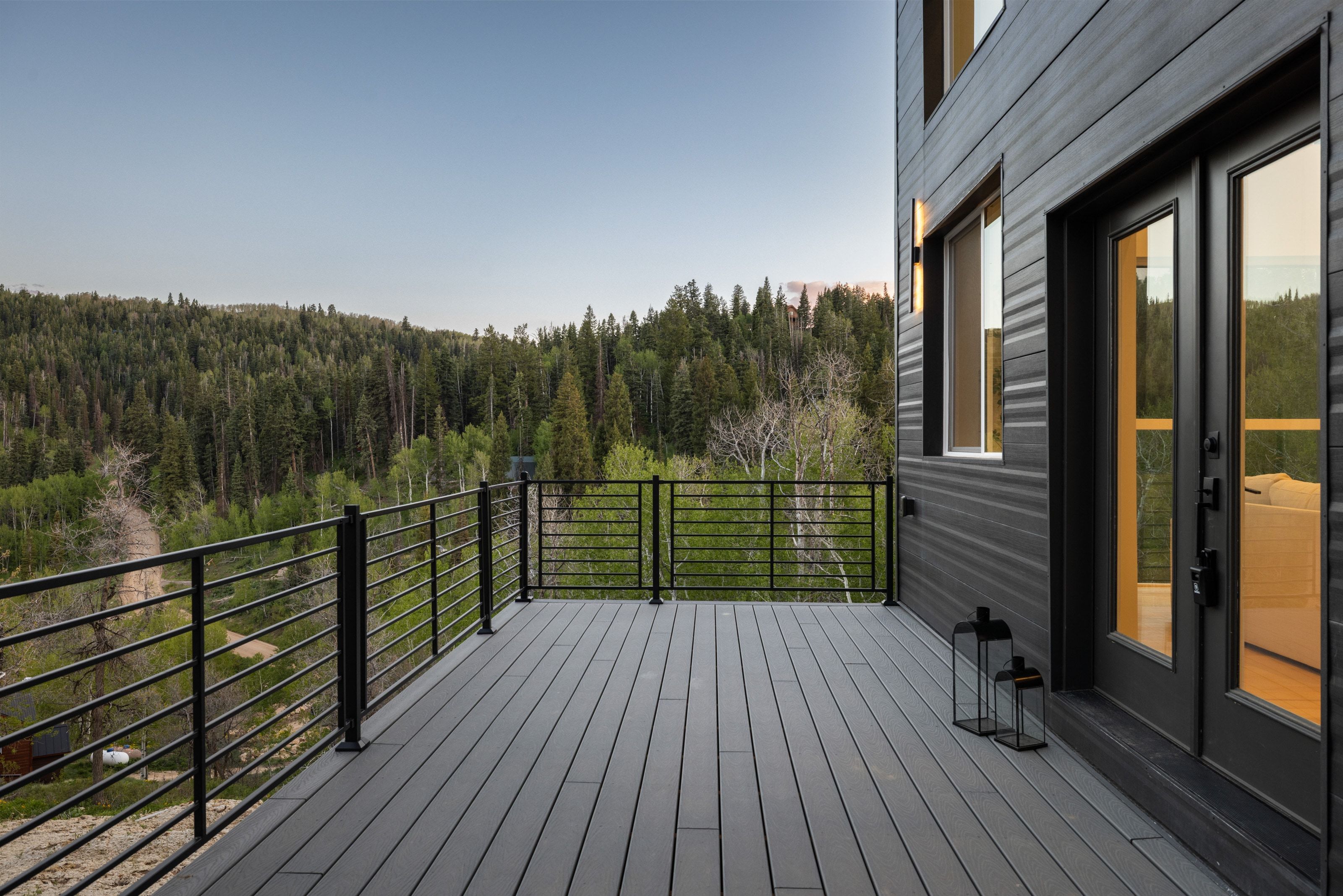 Expansive outdoor deck featuring composite decking, black metal railings, and a contemporary dark-paneled exterior