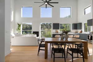 Open-concept living space featuring high ceilings, wood-finish flooring, a modern fireplace, and a kitchen with dark cabinetry and light countertops