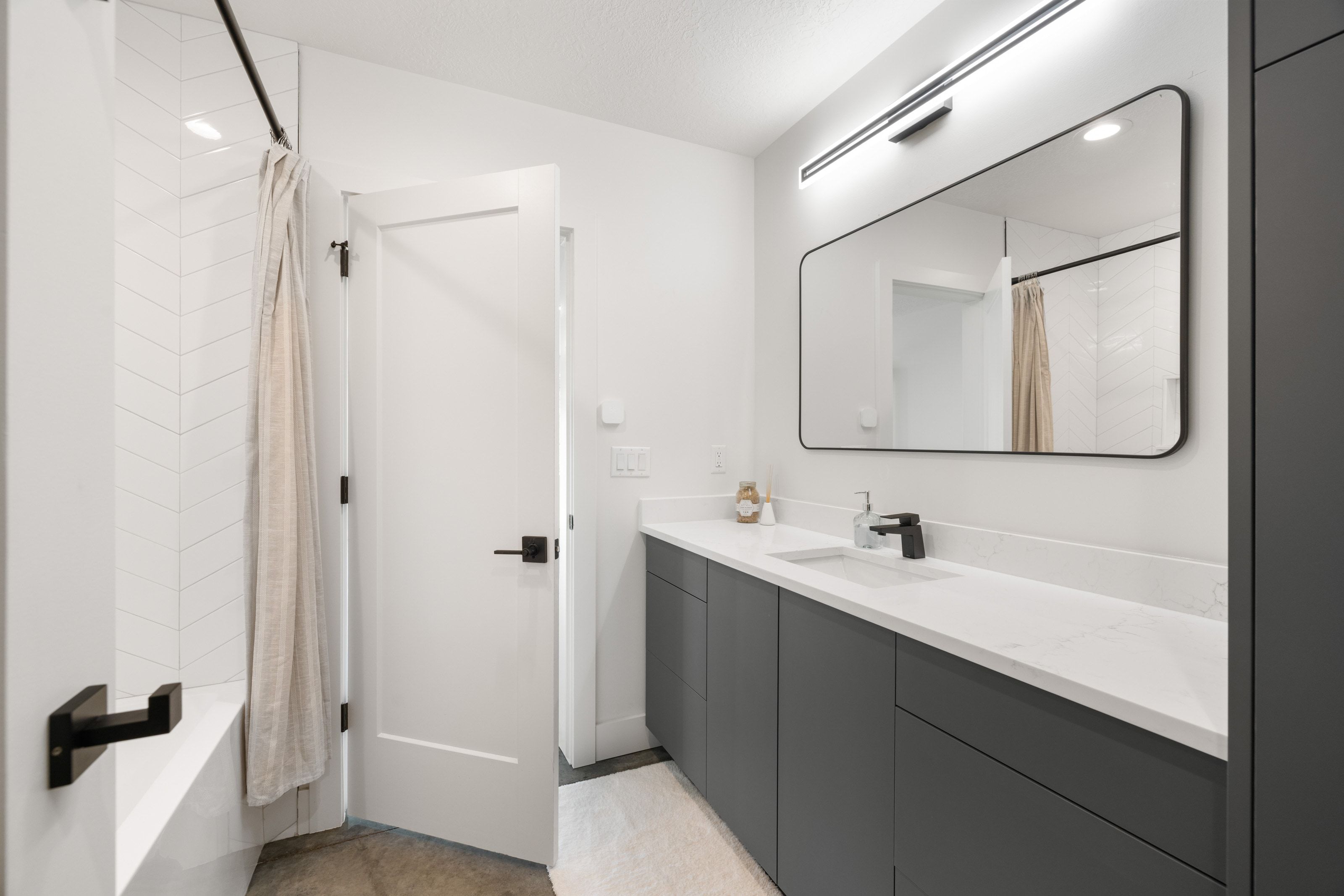 Modern bathroom featuring a single vanity with a white countertop, undermount sink, and matte black faucet