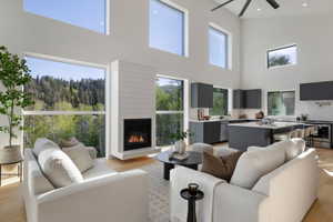 Vaulted ceilings with abundant natural light, a contemporary fireplace with shiplap-style surround, a modern kitchen featuring dark cabinetry and a central island, and wood-finish flooring throughout