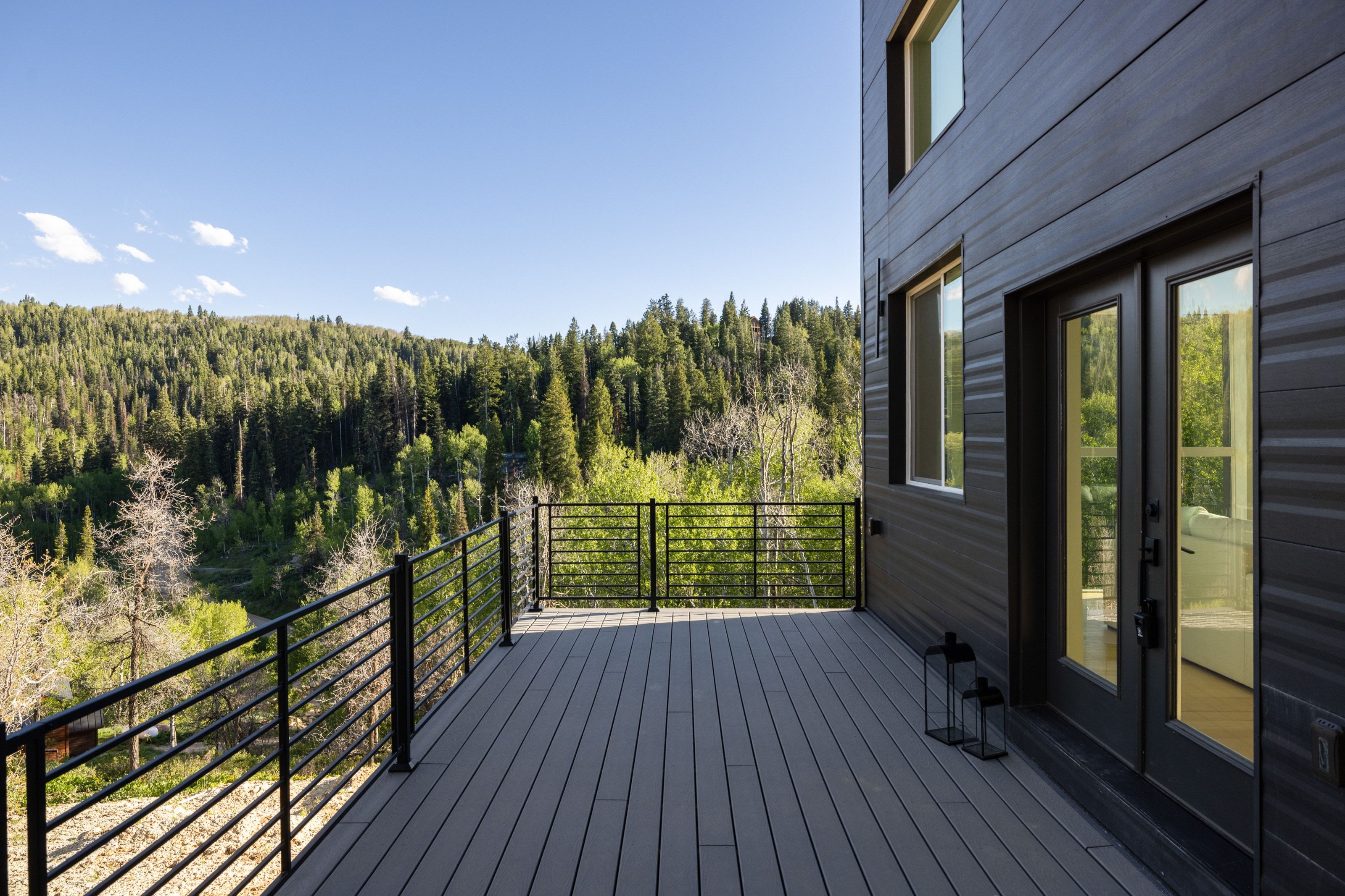 Expansive outdoor deck with composite decking, black metal railings, and dual French doors
