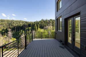 Expansive outdoor deck with composite decking, black metal railings, and dual French doors