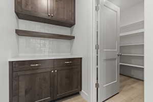 Dark wood-finish cabinetry with silver hardware, white countertop, and white square tile backsplash