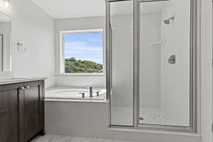 Bathroom featuring a corner soaking tub with a window, a dark wood-finish vanity with a light-toned countertop, and a glass-enclosed shower with hexagonal tile flooring and brushed nickel fixtures