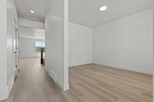 Open concept interior featuring light wood-finish flooring, white walls, and recessed lighting