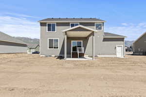 Rear exterior featuring a covered patio, sliding glass door, white railing, and an additional exterior door