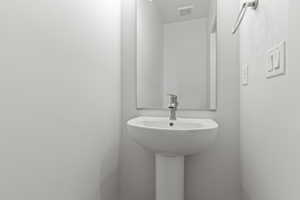 Pedestal sink with a modern faucet and a rectangular wall mirror