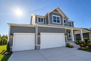 Contemporary two-story exterior with horizontal and vertical siding, featuring a covered porch entry, multiple white-framed windows, and an attached two-car garage with carriage-style exterior lighting