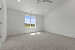 Spacious room featuring neutral carpeting, recessed lighting, a contemporary ceiling fan, and a large window offering outdoor scenery