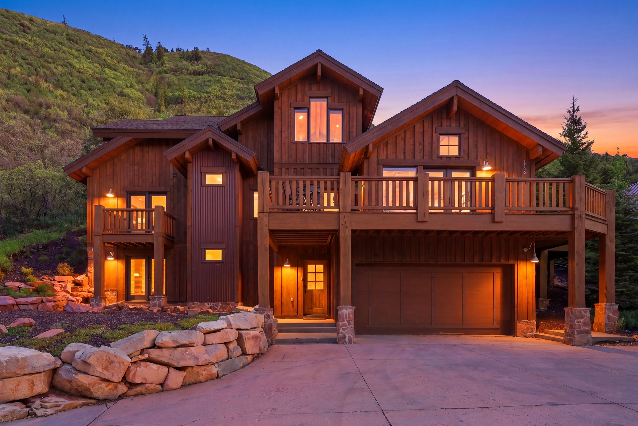 Multi-level wood-clad residence featuring multiple balconies with wood railings, a multi-car garage, and stone accent pillars